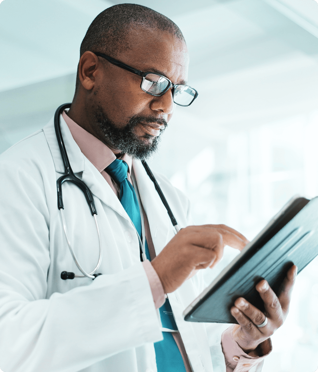 Male doctor focused while updating patient charts on a tablet.